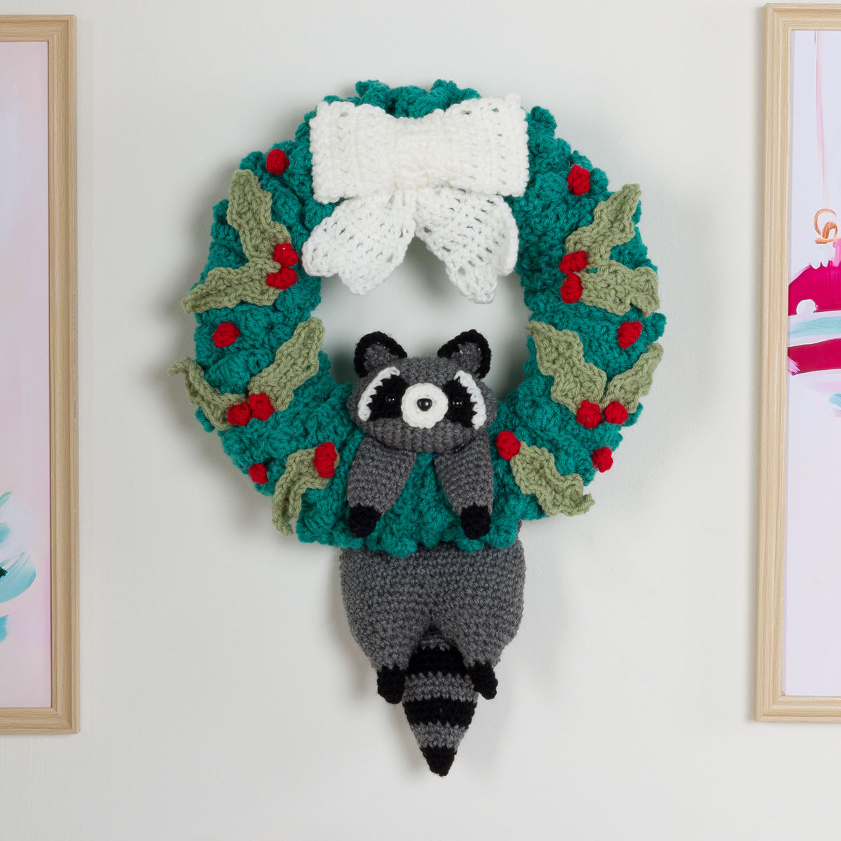 Crocheted raccoon with a crocheted wreath using Red Heart yarns.