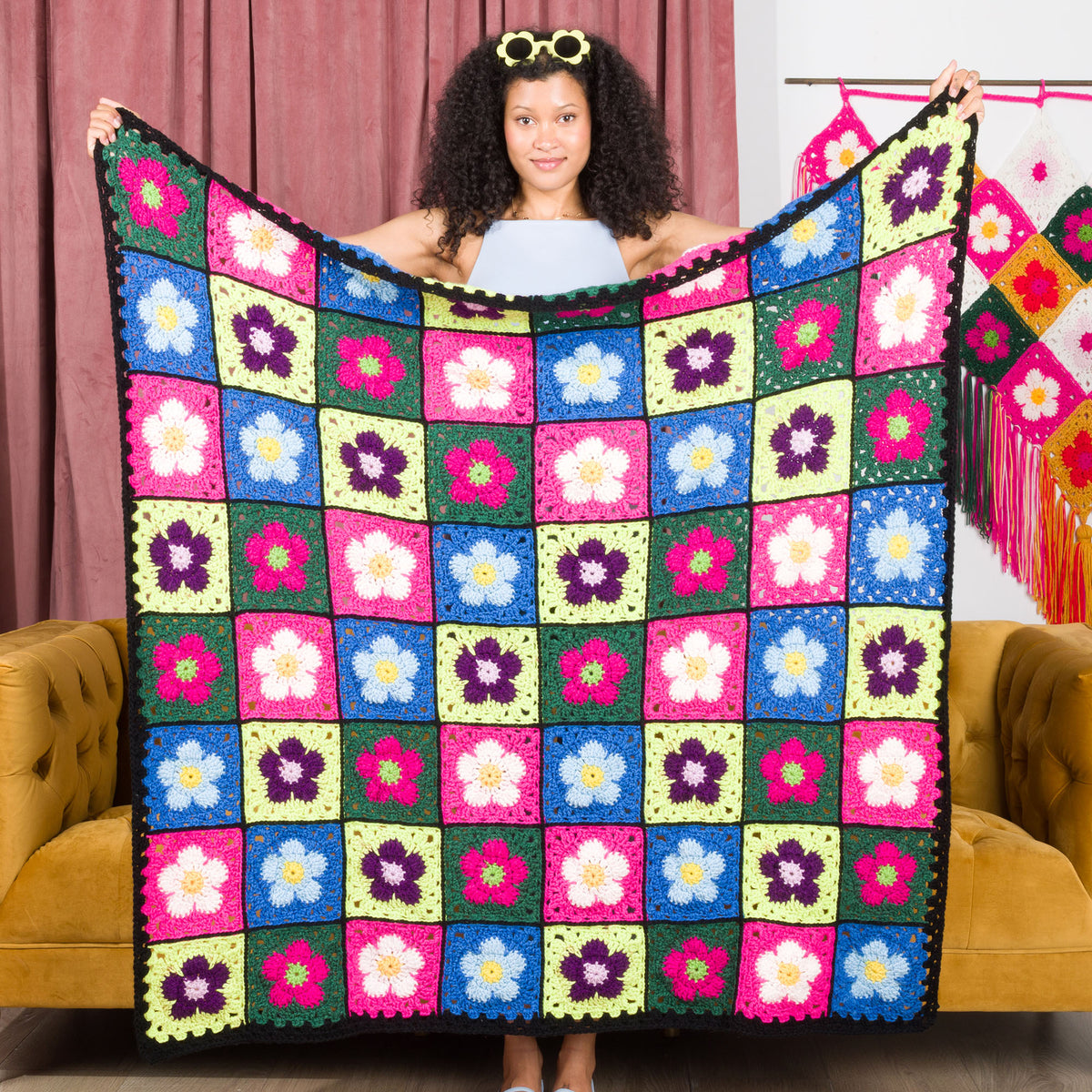 A crocheted blanket with a colorful floral pattern made using Red Heart All in One Flower Power yarn, Version 1