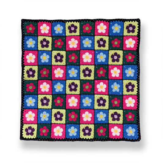 A crocheted blanket with a colorful floral pattern made using Red Heart All in One Flower Power yarn, Version 1