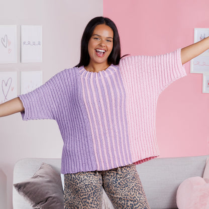 Red Heart Split Decision Crochet Top Woman wearing a purple and pink striped crochet sweater in a room with a pink and white wall.