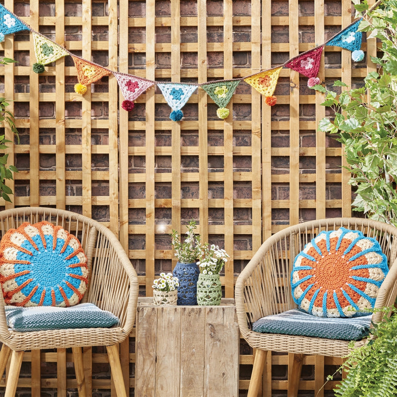A beautifully decorated patio featuring handmade yarn projects made with Yarnspirations yarns, highlighting designs from the Outdoorsy pattern collection.