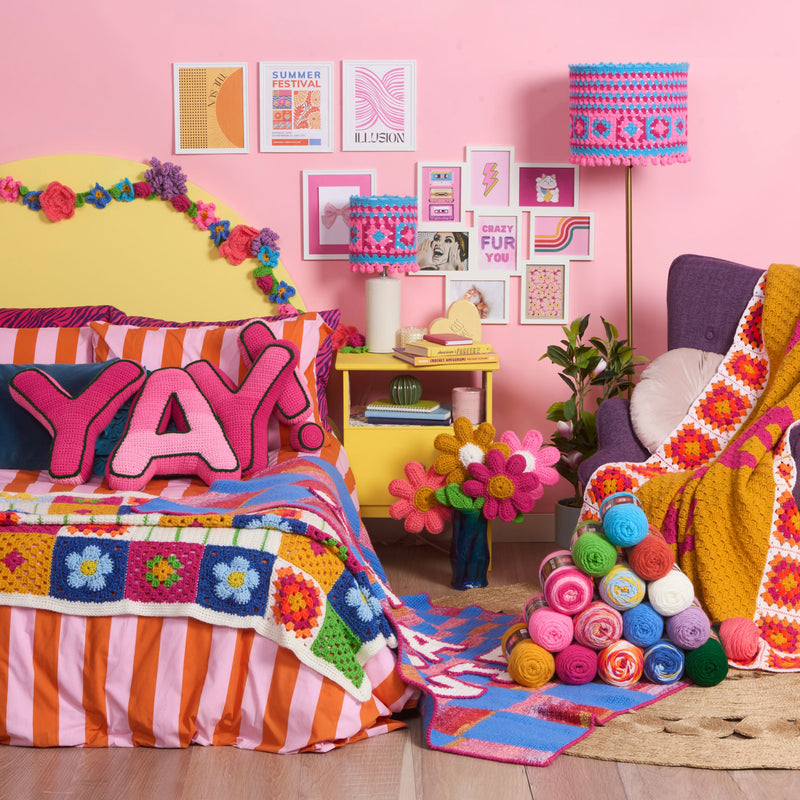 Pink-themed colorful crochet patterns made with Red Heart Yarns, alongside a vibrant pile of Red Heart yarns, featured in the Dopamine Decor Pattern Collection banner.