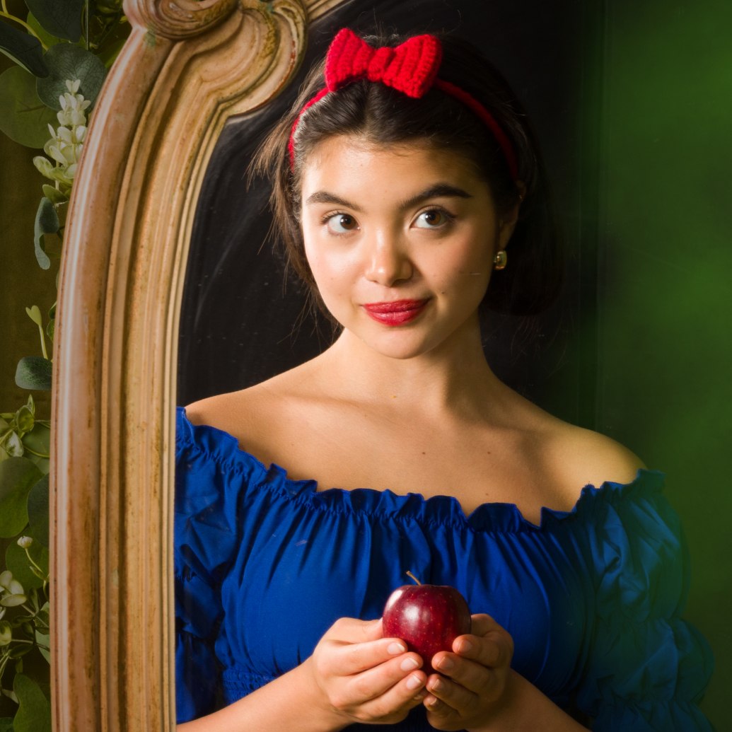 Beautiful woman holding an apple, wearing a crochet headband, looking in the mirror—banner featuring a pattern roundup inspired by the Snow White pop culture theme.
