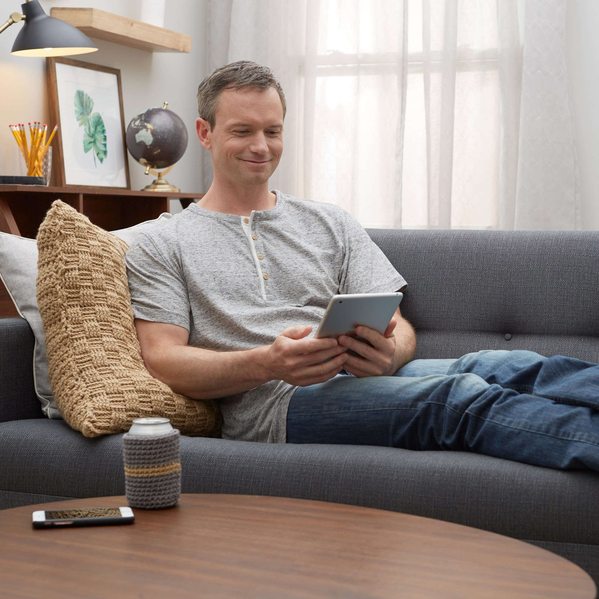 a crochet beer cozy on a coffee table next to a device
